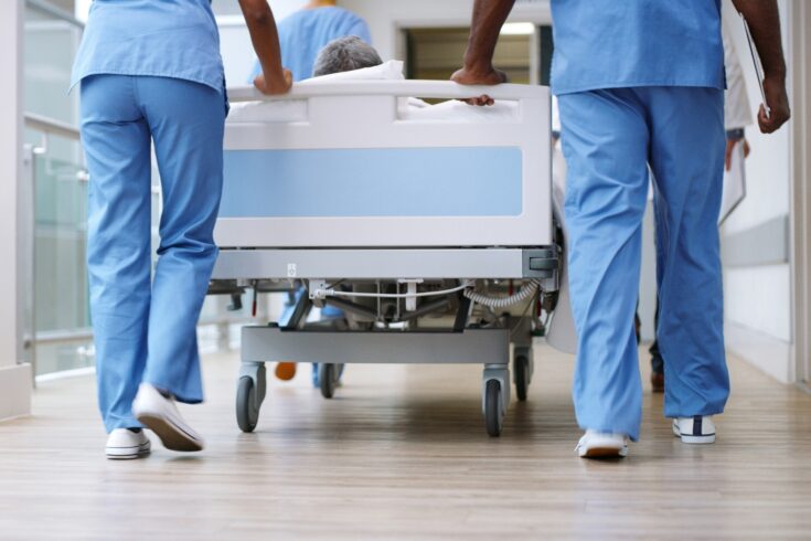 Two medics walking next to a hospital bed