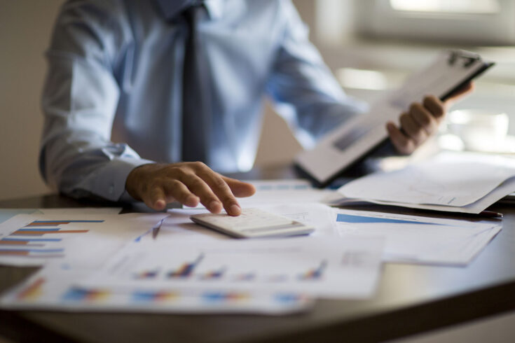 Business accounting concept, business man using calculator with computer laptop, budget and loan paper in office.