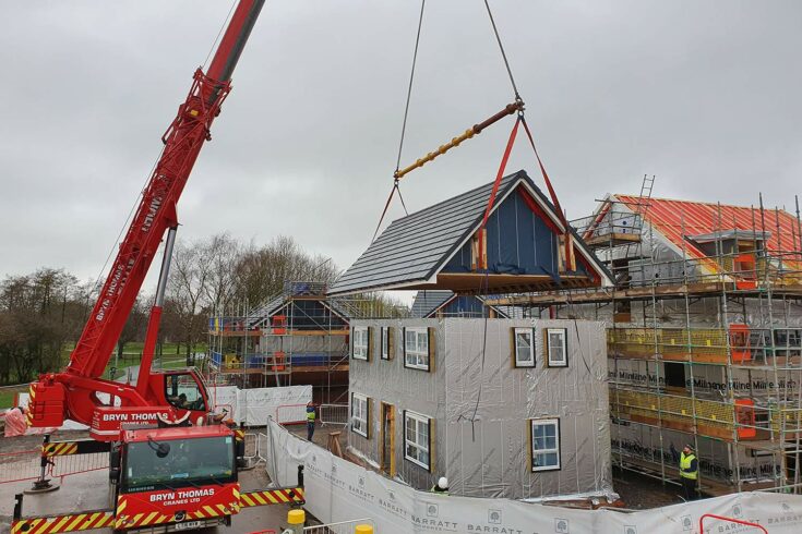 Construction crane lowering roof onto house. Credit: AIMCH.