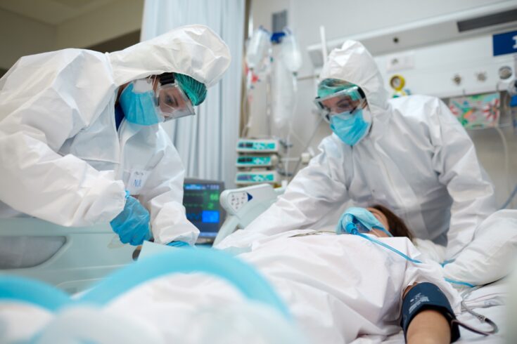 Healthcare workers adjusting equipment to a COVID patient