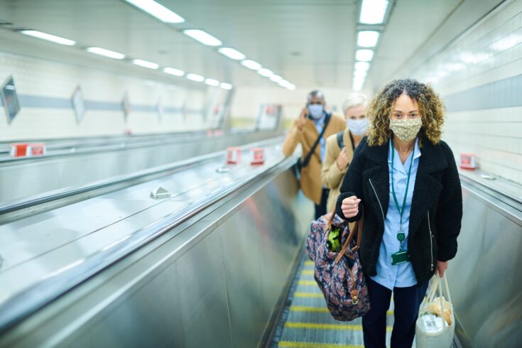 A female commuter on her way to work by underground wearing a face mask