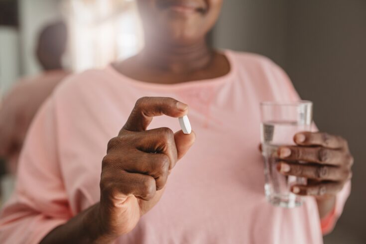 African American woman holding a tablet and glass of water