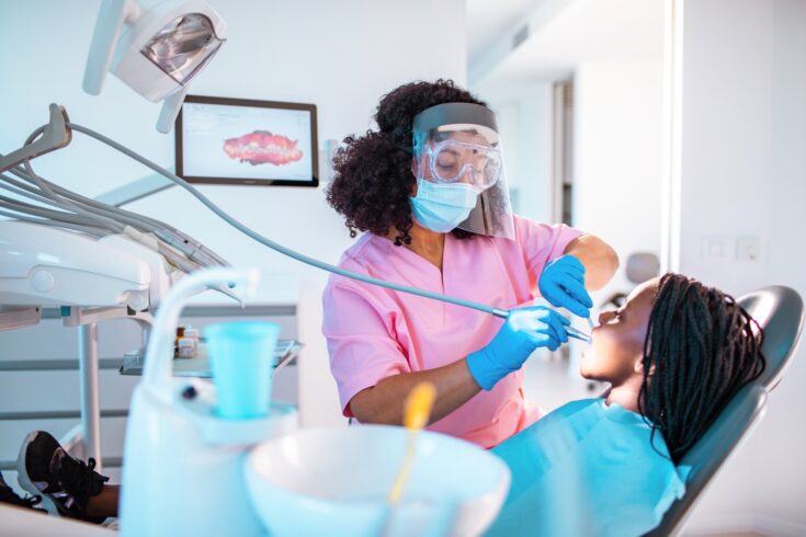 Close up of a girl having a dentist appointment. Dentist wearing PPE