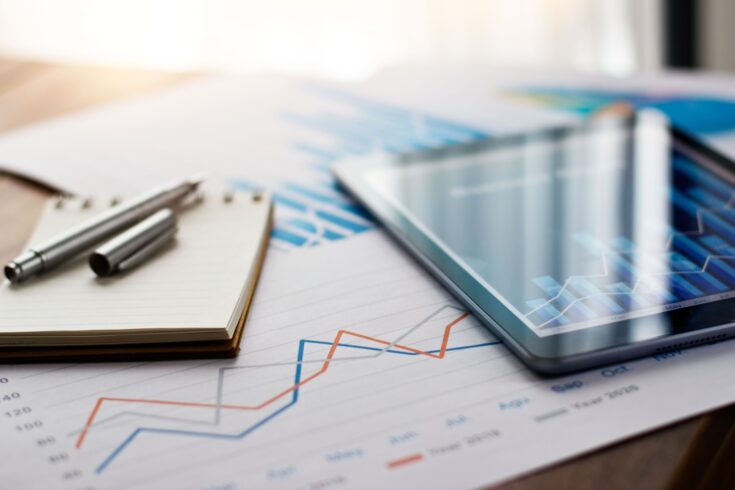 Document report and graph on paper and a tablet with data on a table