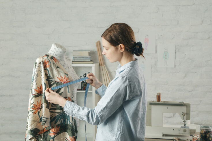 Tailor adjusts garment design on mannequin in workshop.