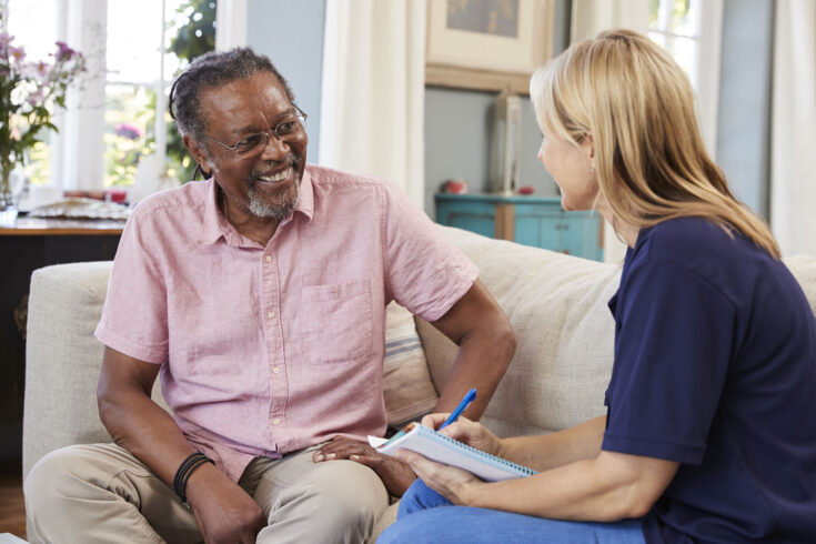 Female support worker visits senior man at home.