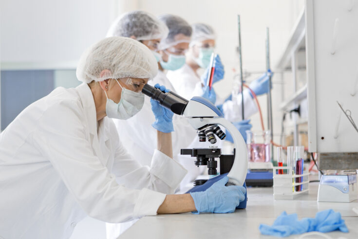 Scientists studying a virus, looking through microscope