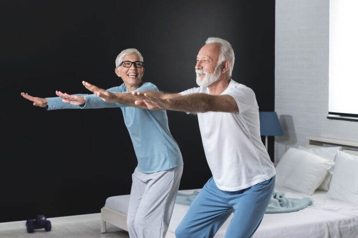 Portrait of happy senior couple performing exercise at home.