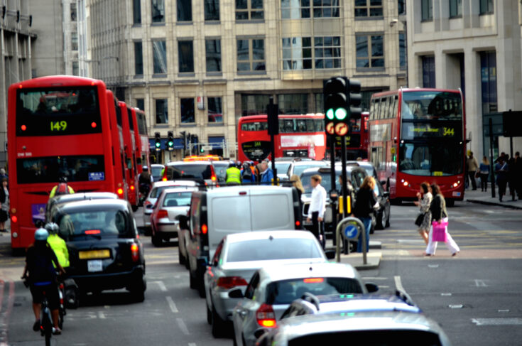 Cars in traffic and people crossing