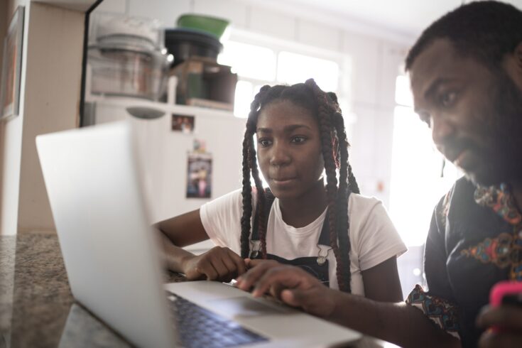 Dad helping his teenager doing homework at home