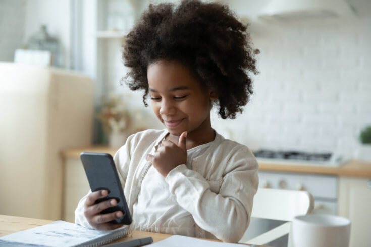 Little biracial girl looking at phone