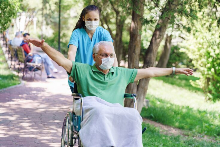 Young female nurse with disabled man in the garden