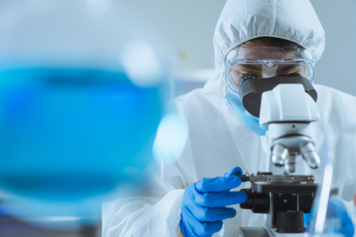 Young Asian handsome man scientist adjust focus and use Microscope to looking biochemical cell in laboratory. Doctor and scientist work in laboratory pandemic of corona virus, COVID19 concept