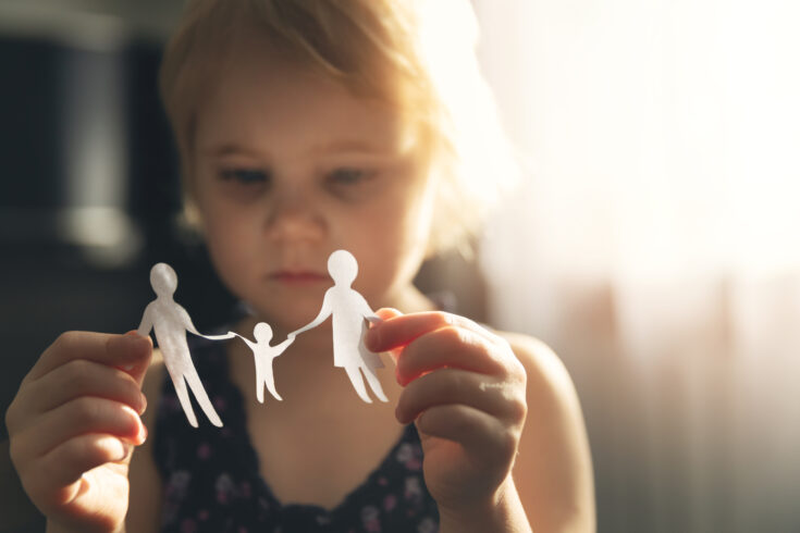 Little girl with paper family in hands