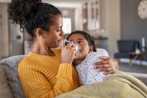 A mother embracing daughter making inhalation with a nebulizer