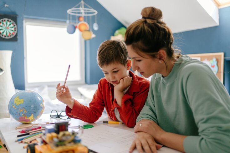 Young boy being homeschooled by his mother in his bedroom