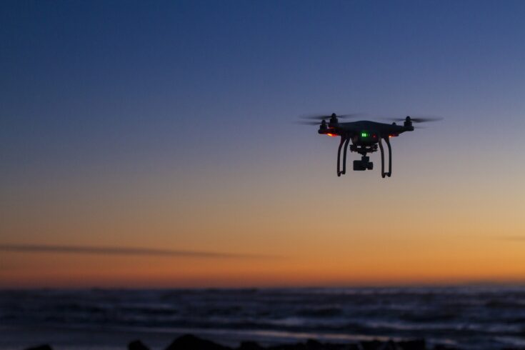 Drone flying over ocean at dawn