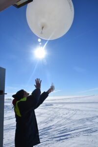 Person stood in snowy environment releasing a weather ballon.