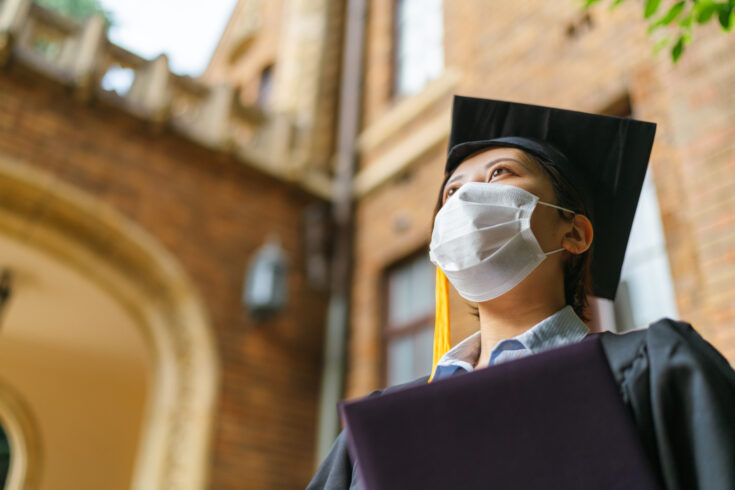 Low angle portrait of student in graduate gown with diploma