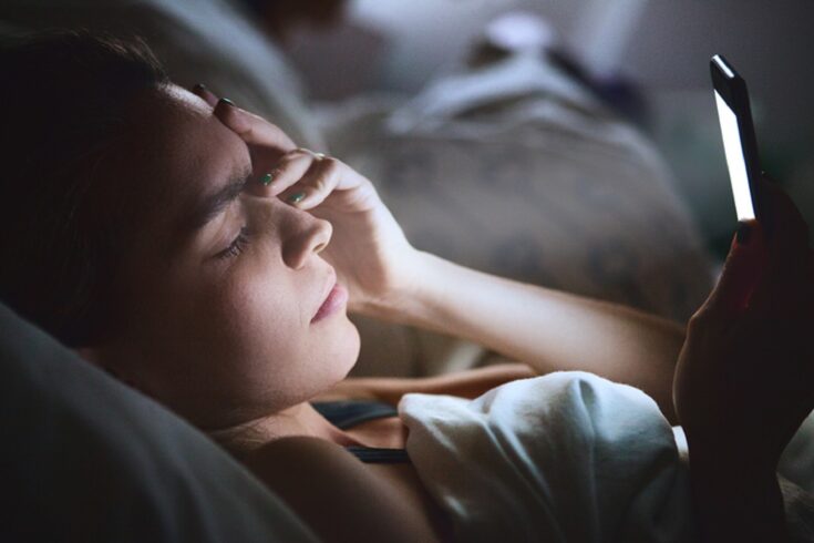 Woman in bed with smartphone