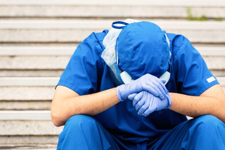 Overworked, male mature health care worker sitting looking down