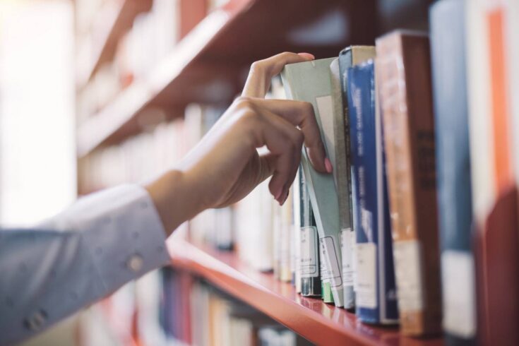 Woman reaching for book in library