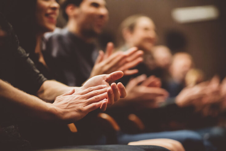 Group of people clapping hands in the theater.