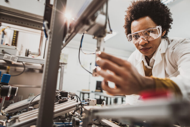 Black female engineer working on industrial machine in a laboratory.
