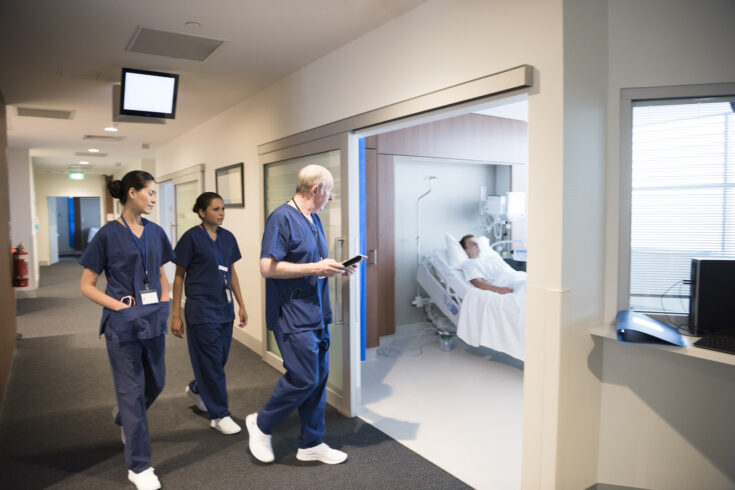 Medical staff in hospital corridor with patient in bed