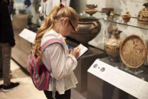 Student looking at artifacts in a case on a trip to the museum.
