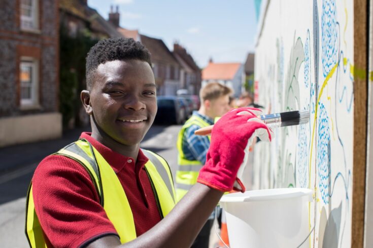 Group of helpful teenagers creating and maintaining community art project