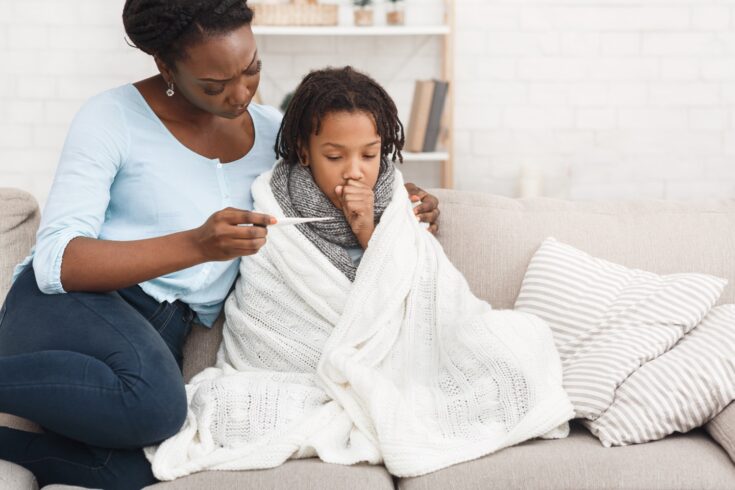 Mother measuring temperature of her sick daughter