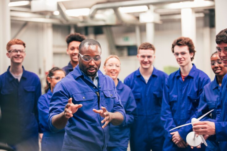 A tutor teaches his class about renewable energy in an engineering workshop