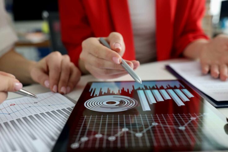 Business women studying charts and diagrams on digital tablet closeup