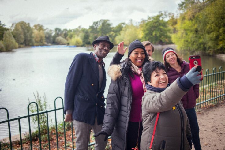 Diverse group of people taking a selfie in front of a lake in a park