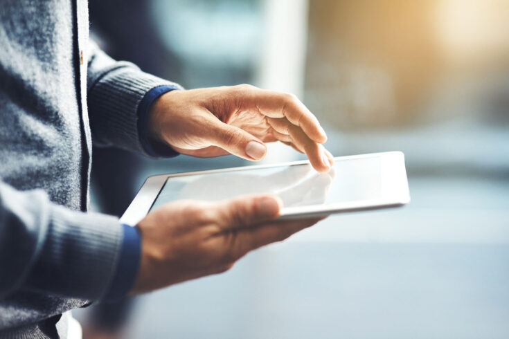 Closeup shot of an unrecognisable businessman using a digital tablet in an office.