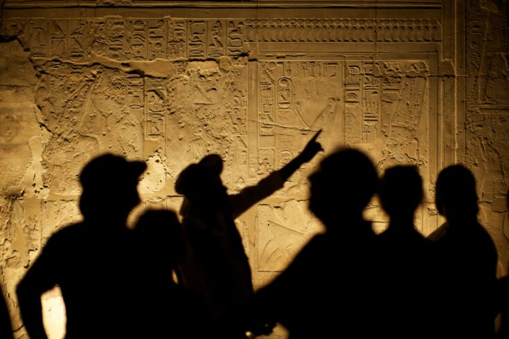 Egyptian Hieroglyphs with tourist archeologist silhouettes