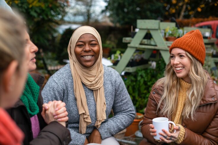 A diverse group of volunteers sitting outdoors wearing warm casual clothing on a sunny cold winters day