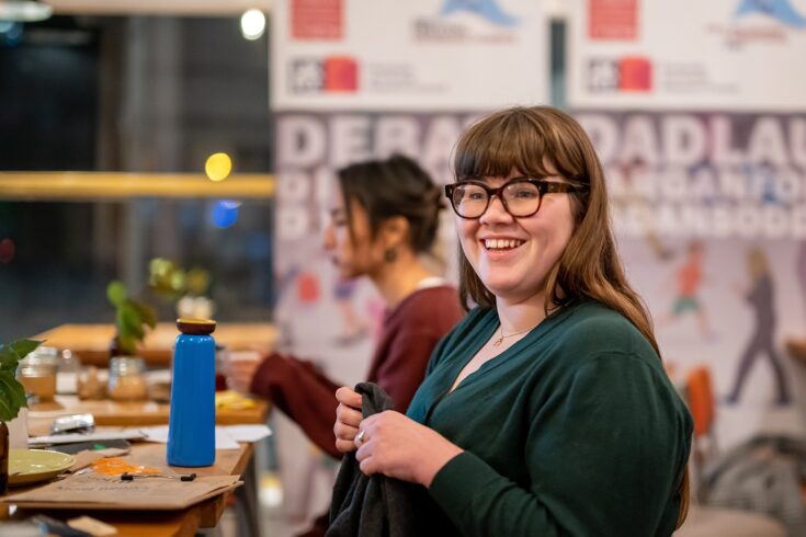 A smiling young woman working at a table at the Festival Science workshop