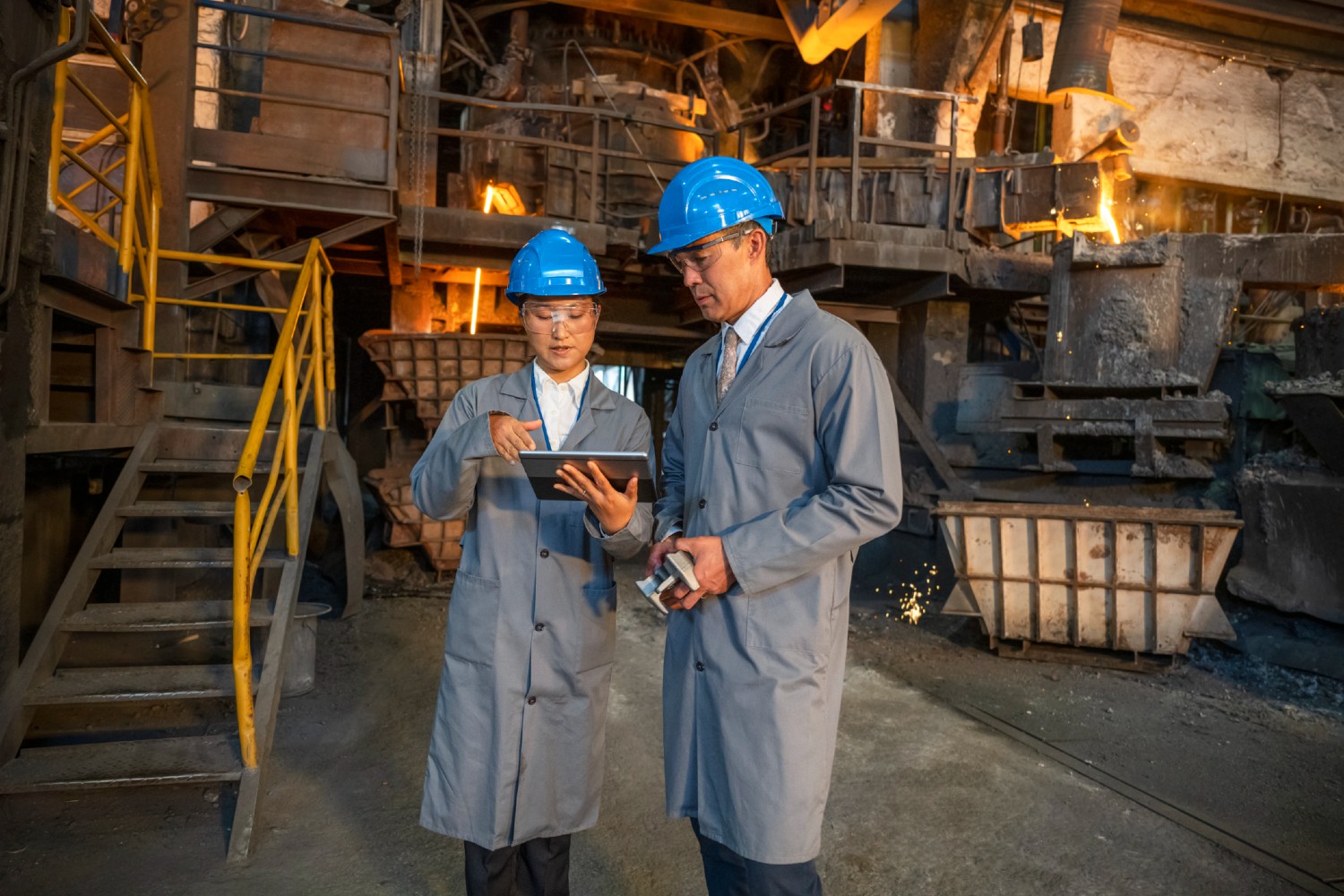 Male and female engineers using a digital tablet while standing in the foundry
