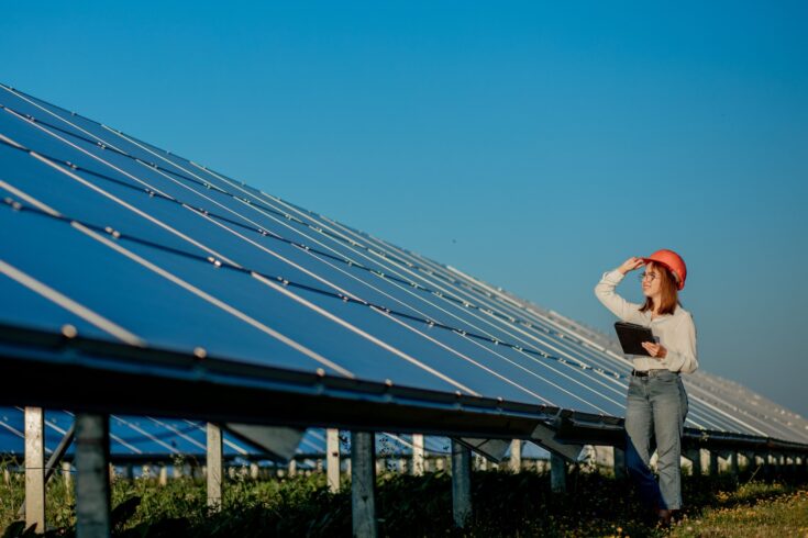 Female inspector engineer holding digital tablet working in solar panels power farm