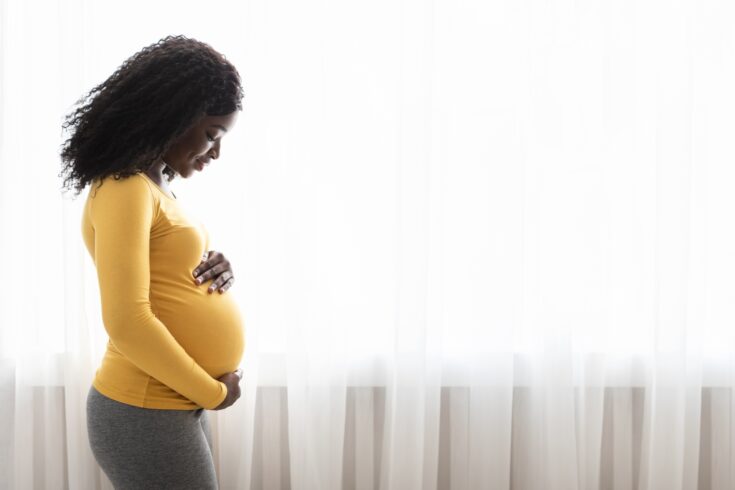 Pregnant black woman hugging her tummy