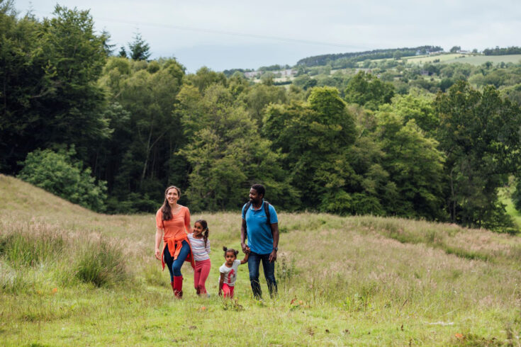 Happy family walking up through the grassy hills in Northumberland.