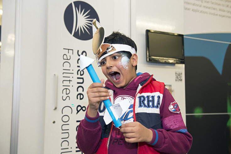 A boy excitedly holds a small paper rocket