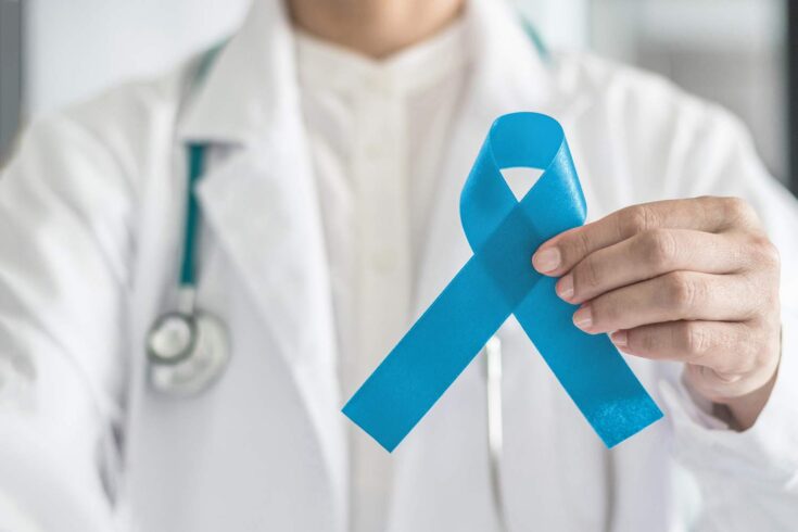 doctor holding a blue ribbon, a symbol for prostate cancer awareness