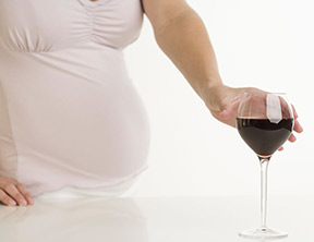 Pregnant woman reaching for wine glass