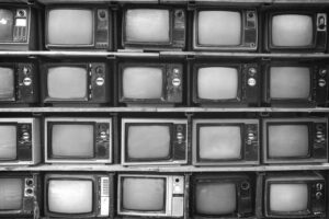 Black and white photo of stacked up vintage tv sets stacked