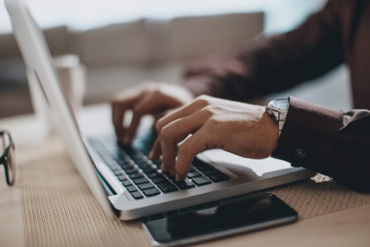 Hands typing on a laptop computer