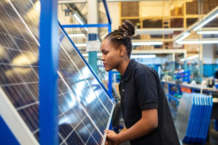 Side view of a female employee inspecting newly manufactured solar panels in company