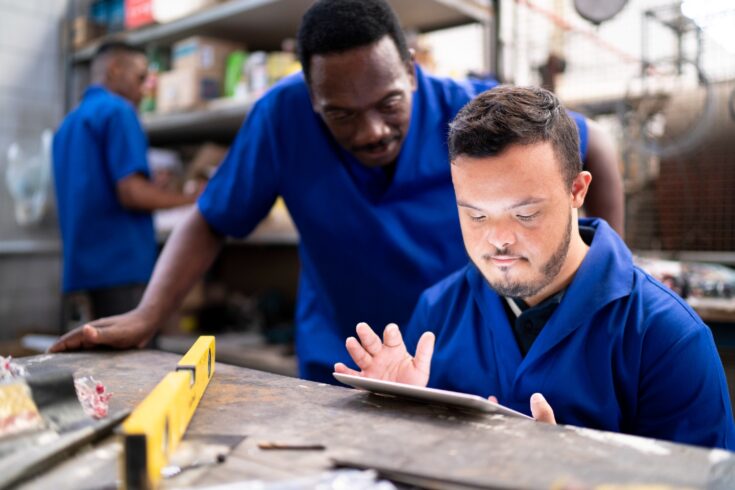 Two work colleagues using digital tablet and working in industry